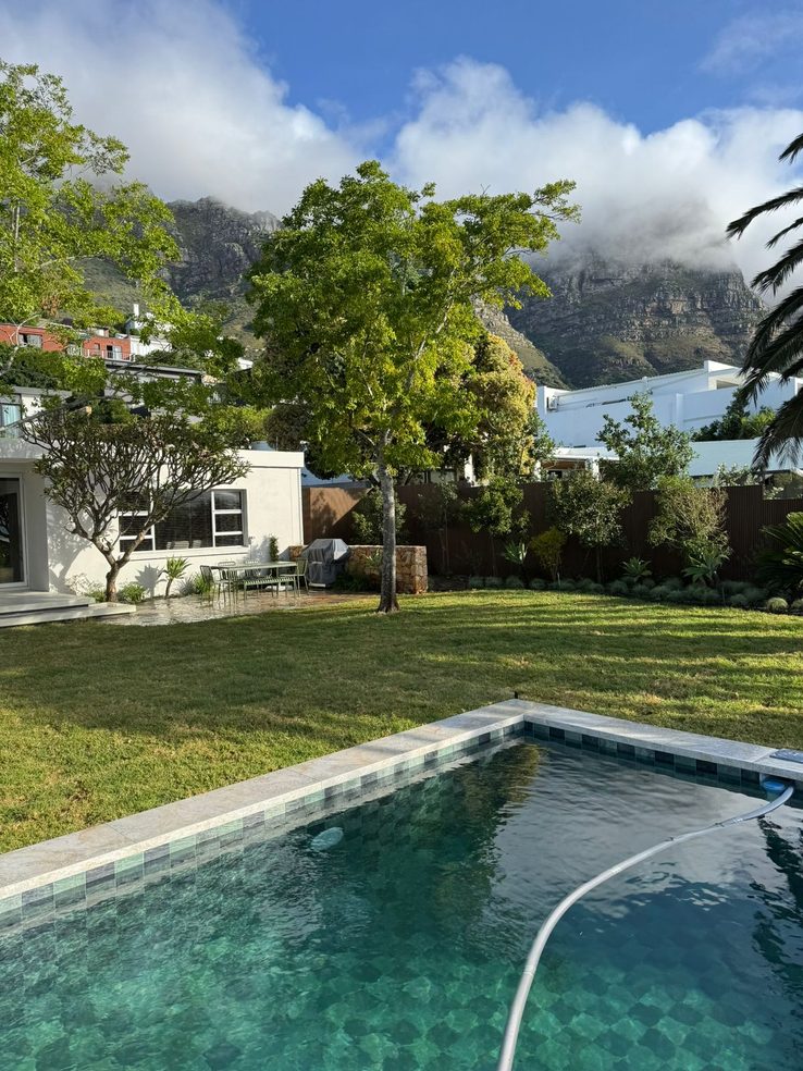The same garden after landscaping — a new pool set in level lawn with mountains behind