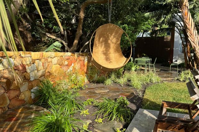 Stone-clad courtyard garden with hanging chair and layered planting