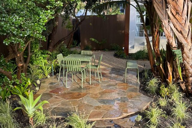 Natural flagstone patio with garden chairs, fresh planting and corten steel screening