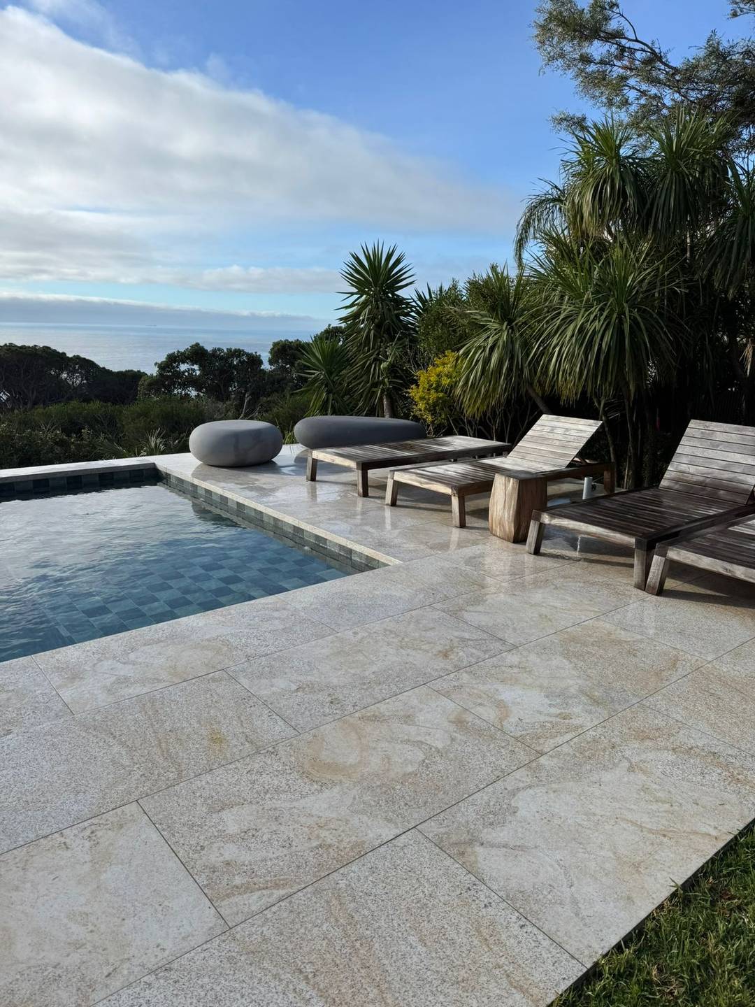 Sun loungers on a travertine pool deck overlooking the sea